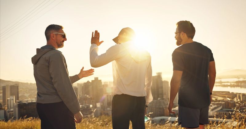 Fitness, men and mountain with high five for workout, achievement or winning in nature sunset. Back view, male people or friends with success for exercise, celebration or teamwork in outdoor training