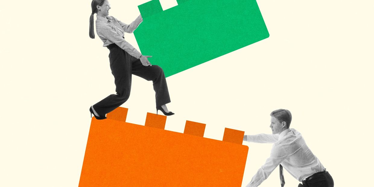 Two businesspeople assembling giant green and orange puzzle pieces.