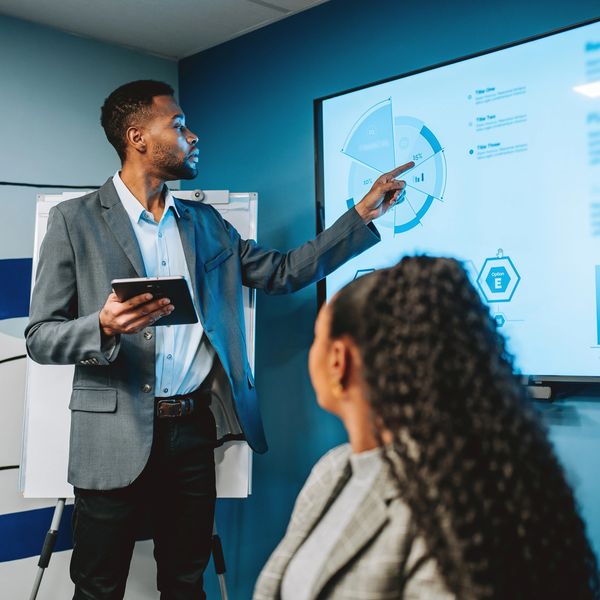 Man presenting data on a screen in a meeting.