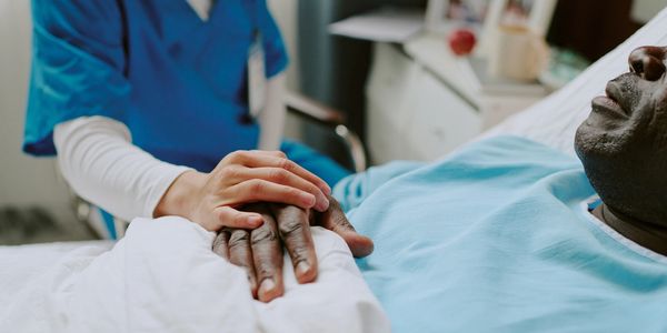 A nurse comforting a patient by holding his hand in a hospital.