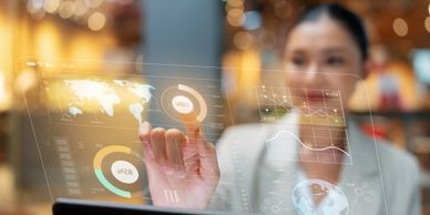 Woman interacting with futuristic transparent digital interface displaying global data and charts.
