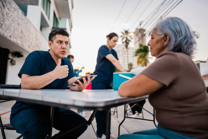 Mid adult nurse man talking to senior woman outdoors