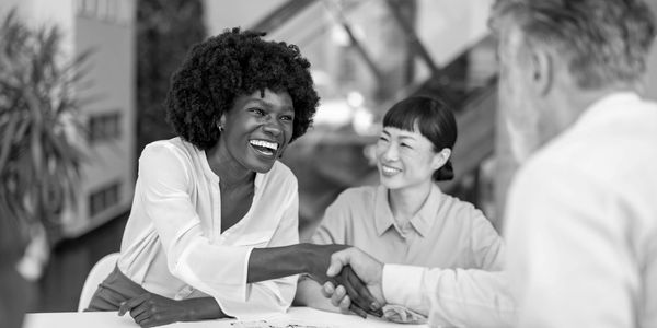 People shaking hands and smiling in an office meeting.