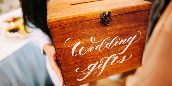 Wooden box labeled 'Wedding gifts' held by a person.