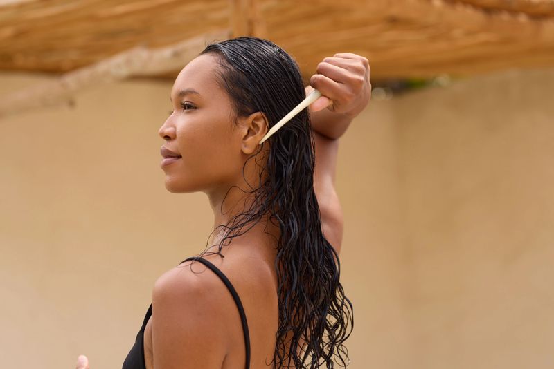 A woman with sleek, wet hair uses a wide-tooth comb, illustrating a serene and effective hair care routine. The image conveys themes of self-care, beauty, and daily grooming rituals.