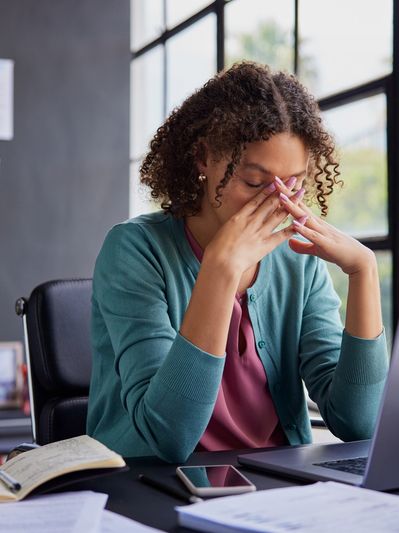 Stressed woman at work, massaging her nose bridge.