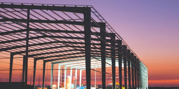 Steel framework of a building under construction at sunset.