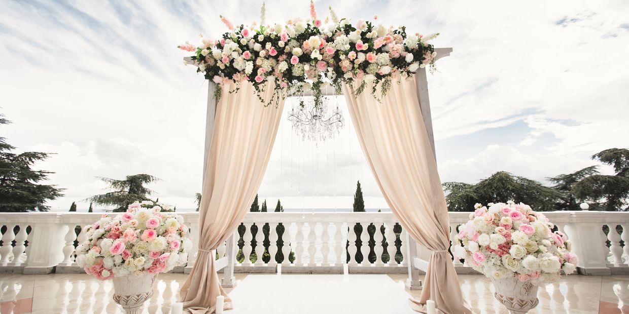 Elegant wedding arch decorated with flowers and drapes