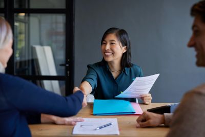 Woman shaking hands during a meeting with documents.