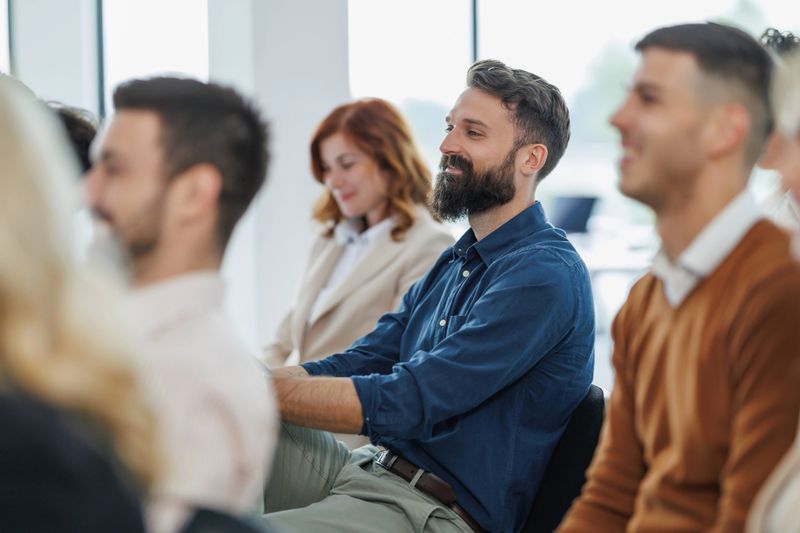 A group of business professionals attentively participating in a corporate training session. The image captures diverse individuals focused on gaining new skills and knowledge in an office environment.