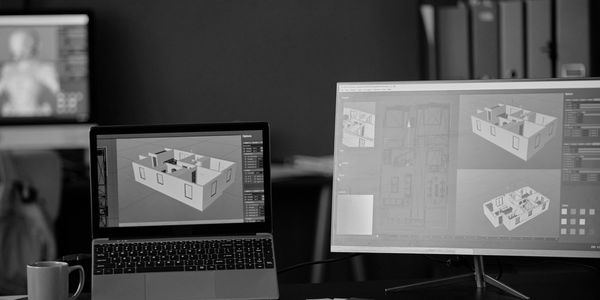 Workspace with laptop and monitor displaying 3D architectural models.