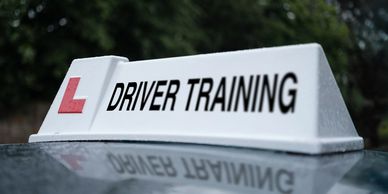 Close-up of a driver training sign on a car roof.