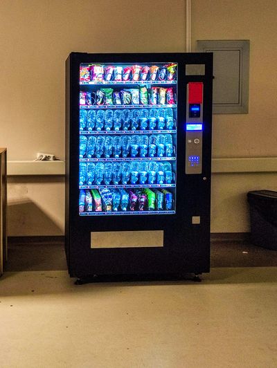 Illuminated vending machine stocked with water bottles and snacks in a dimly lit room.