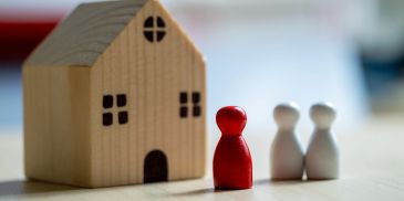 Red and white pawns near a wooden house model.