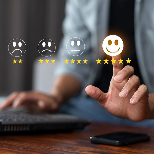 Person selecting a happy face with five-star rating on a virtual feedback interface.