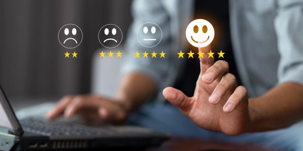 Person selecting a five-star happy face rating on a digital interface.