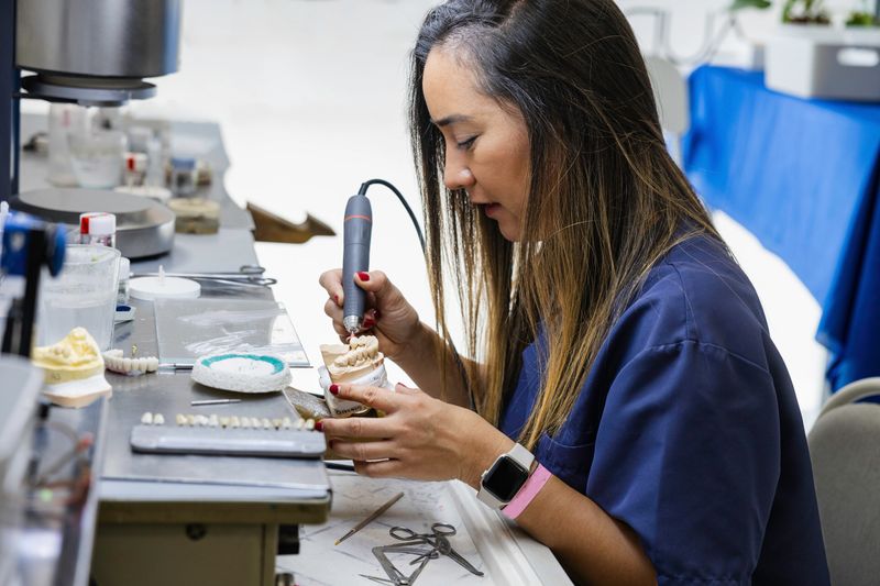 A female dental technician crafting a prosthetic model in a lab.