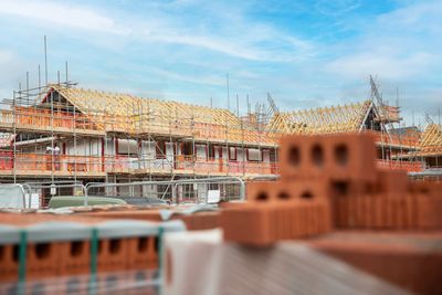 A building under construction with scaffolding and wooden roof frames.