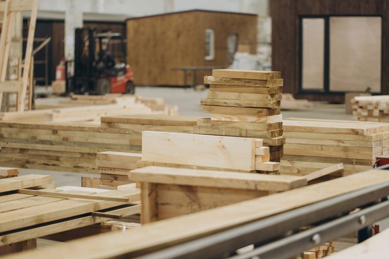 Busy carpentry workshop with neatly arranged wooden planks and beams for modular building projects. Craftsmen create eco-friendly materials with precision and efficiency