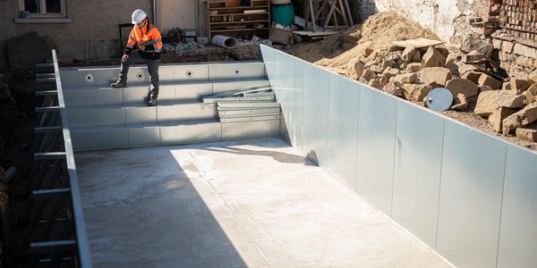 Construction worker inspects materials from the structure of a new pool build.
