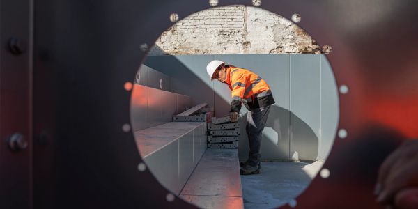 Construction worker inspecting stacked materials through circular frame.