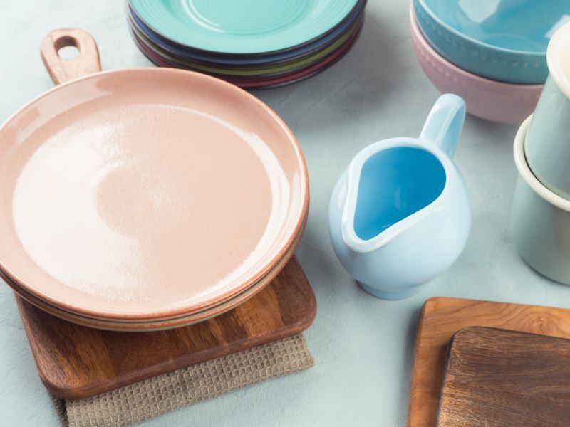 Stylish and elegant pastel color tableware and wooden cutting boards. Dinnerware on turquoise background