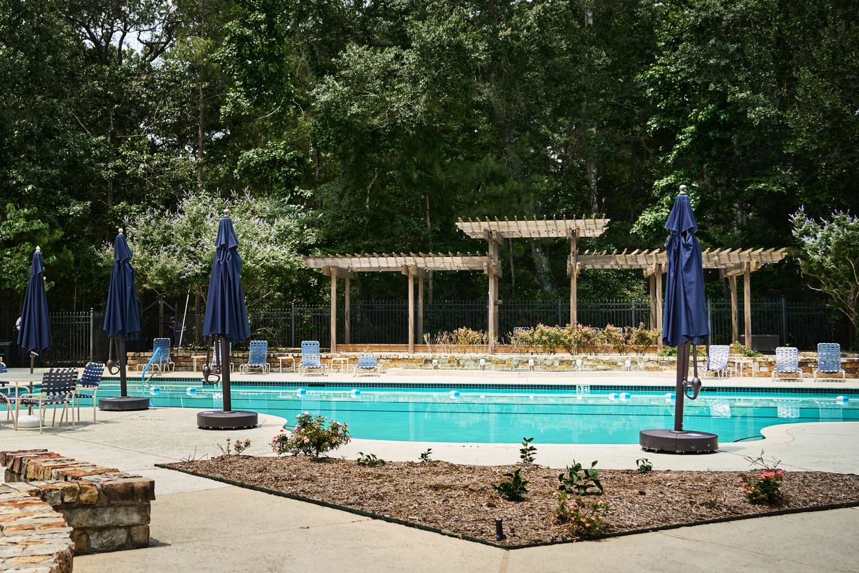 Empty outdoor swimming pool with blue umbrellas and lounge chairs.
