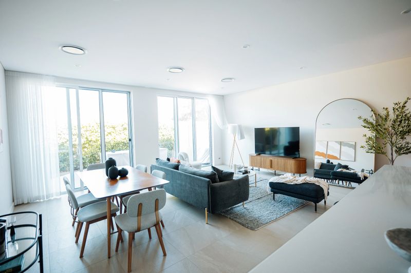 Modern living room with stylish furniture and decor, featuring large windows letting in natural light and a sleek contemporary design