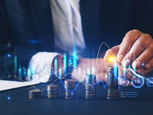 Stacks of coins increasing in height with financial data overlay and a person adding coins.