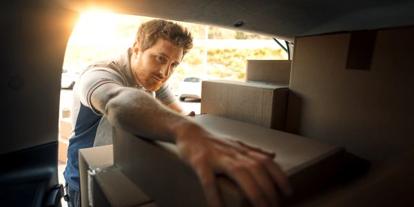 Man loading cardboard boxes into a vehicle.