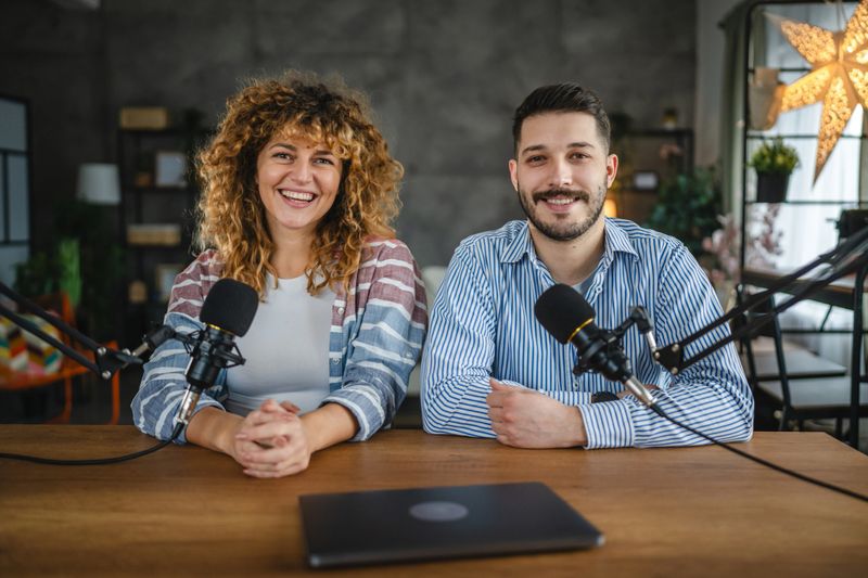 Portrait of two radio hosts laugh and enjoy while record podcast in studio together