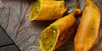 Stuffed and fried chili peppers on a rustic leaf.