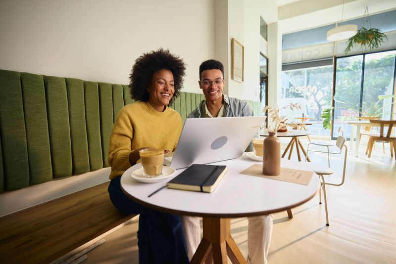 Two university students working on an essay together in a modern coffee shop. High quality photo