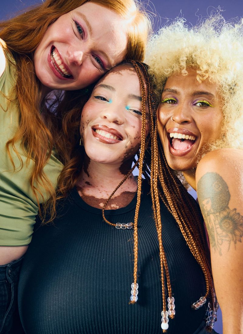 Studio portrait of three diverse young women embracing, demonstrating unity and celebrating diversity