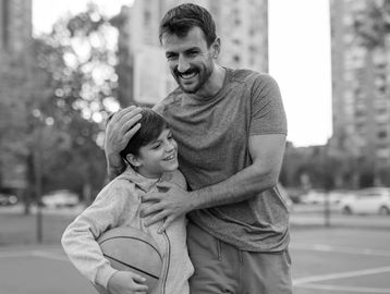 Father and son sharing a joyful moment on a basketball court.
