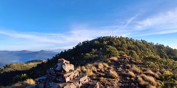 Rock cairn on a mountain trail under a clear blue sky.