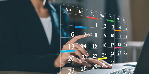 Person interacting with a futuristic digital calendar interface above a laptop.