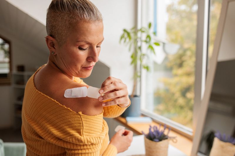 Woman in the comfort of her home applies a hormone replacement therapy patch to her shoulder.