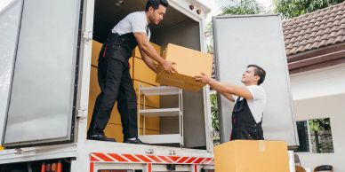 Two men loading boxes into a truck.