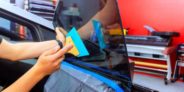 Person applying tint film to a car window.