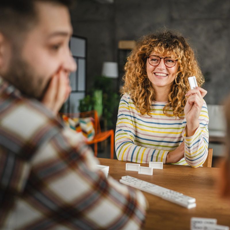 front view of mother play dominoes game with husband and son