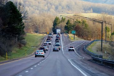 Traffic on a highway surrounded by trees and hills.
