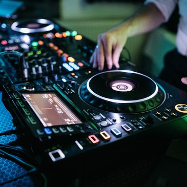 Close-up of a DJ mixing music on a digital controller with colorful lights.