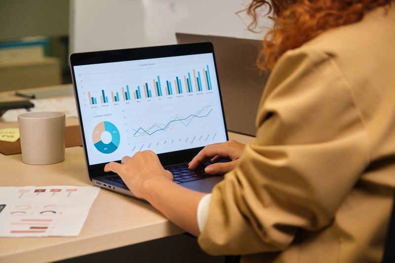 Businesswoman working on laptop, analyzing financial charts and data for business strategy
