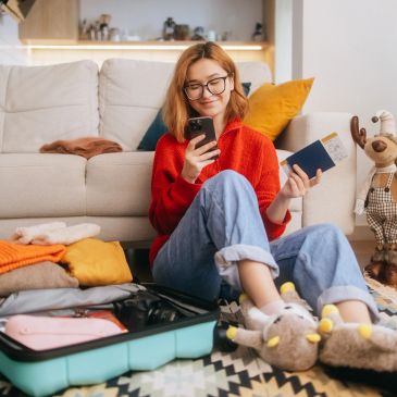 Woman packing suitcase and looking at phone.