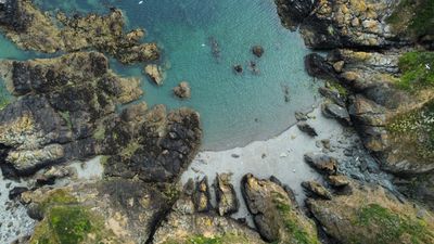 Aerial view of rocky coastline and clear water.