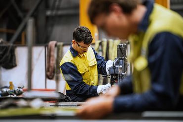 Workers operating machinery in a workshop.
