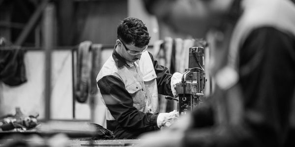 Worker operating machinery in an industrial setting wearing safety glasses.