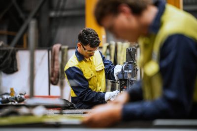 Two workers operating machinery in a factory.