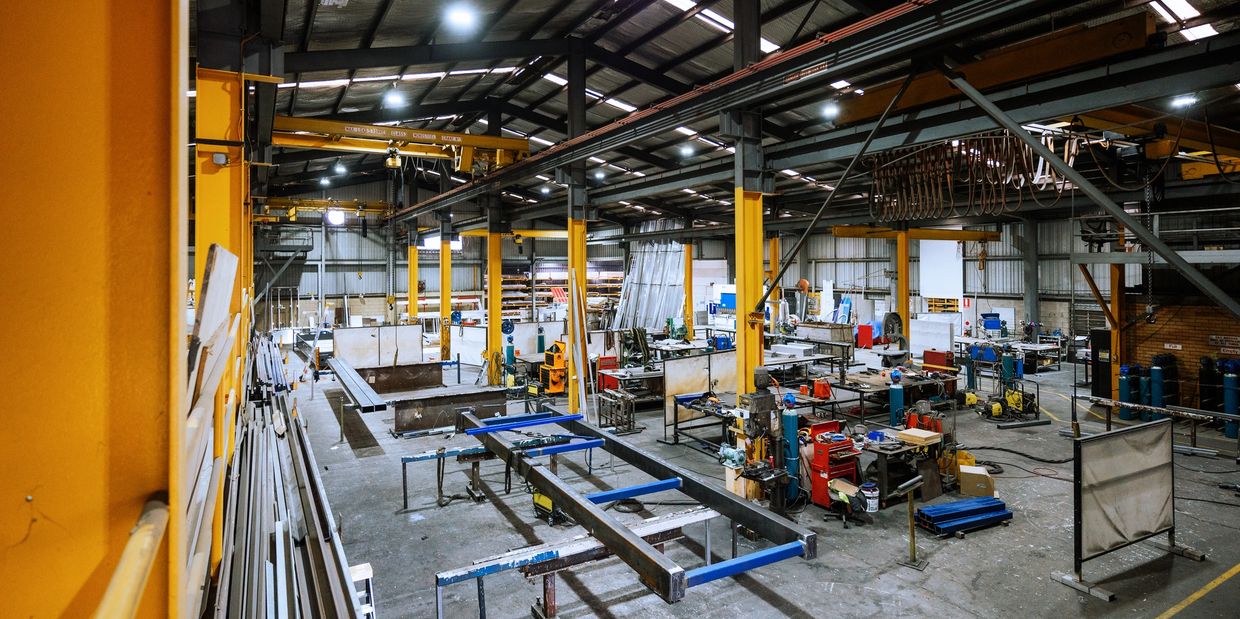 Inside a spacious, well-lit industrial workshop with machinery and metal structures.